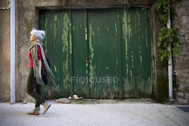Вид сбоку на женщину, идущую по улице. Bruniquel, France — стоковое фото