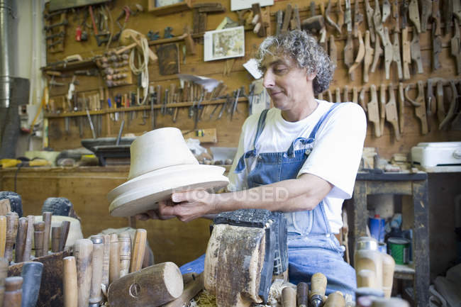 Carpintero admirando el molde de madera para la cabeza en el taller - foto de stock