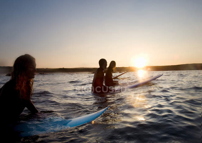 Чотири людини сидять на дошках для серфінгу — стокове фото