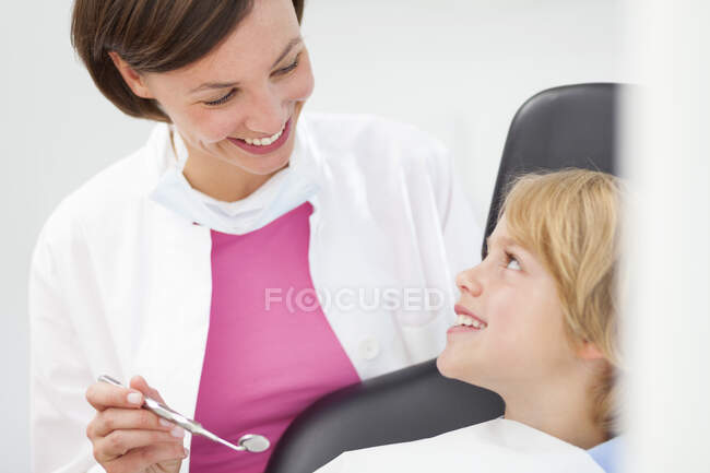 Хлопчик перевіряє, стоматолог тримає дзеркало для зубів — стокове фото