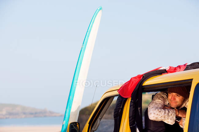 Mann in Lieferwagen lächelt mit Surfbrett — Stockfoto