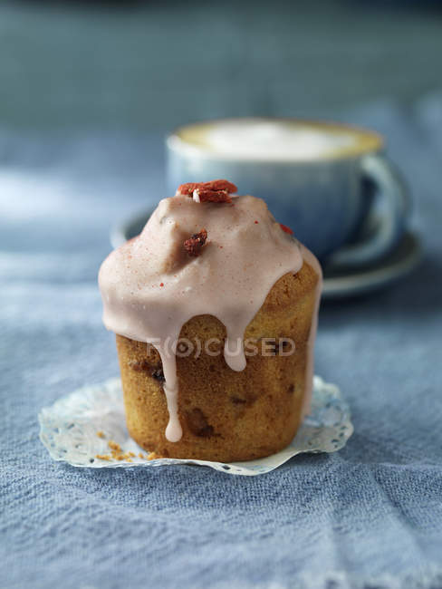 Strawberry icing muffin on blue tablecloth — Stock Photo
