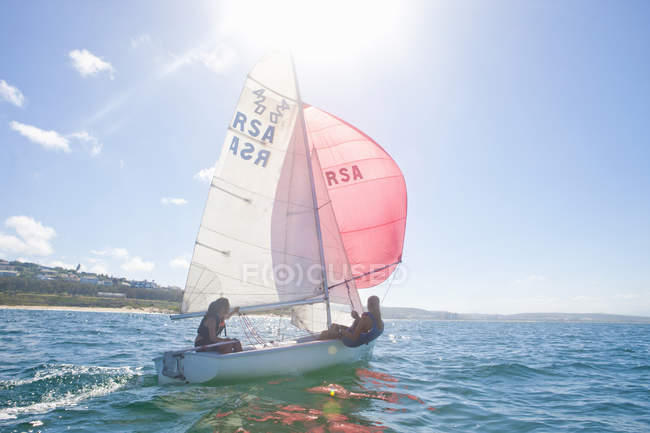 Teenagers riding sailing boats in sea water with backlit — Stock Photo
