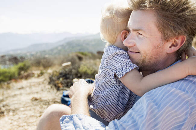 Mature man and toddler daughter hugging, Calvi, Corsica, France — Stock Photo