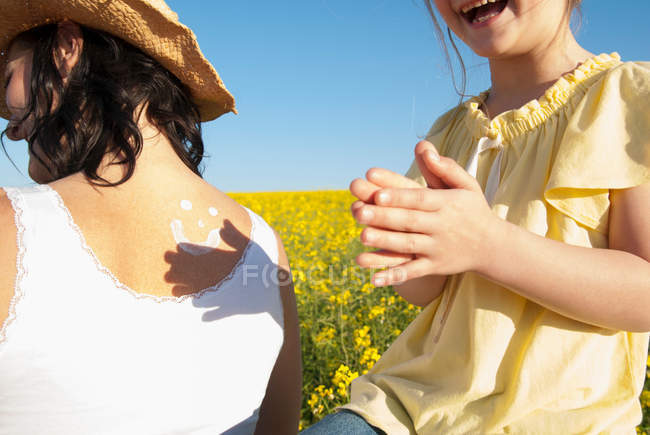 Chica frotando protector solar en las madres espalda - foto de stock