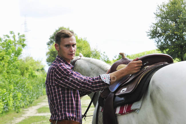 Портрет молодого чоловіка сідло коня — стокове фото