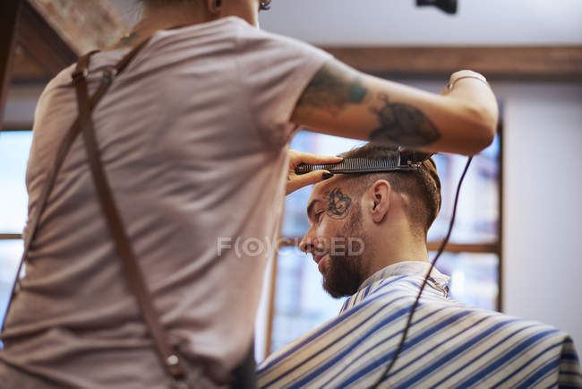 Coiffeur rasage des cheveux du client — Photo de stock