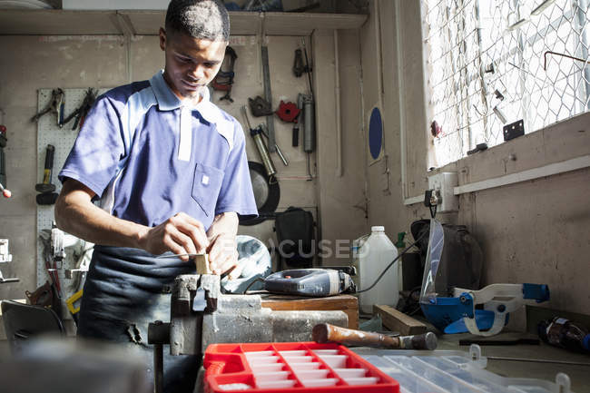 Young man working at vice in repair workshop — Stock Photo