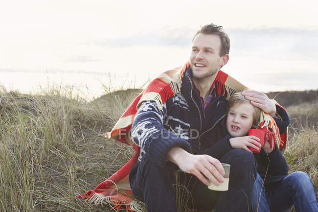 Lächelnder erwachsener Mann und Sohn auf Sanddünen — Stockfoto