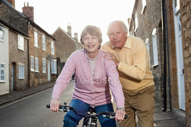 Муж поддерживает жену на велосипеде — стоковое фото