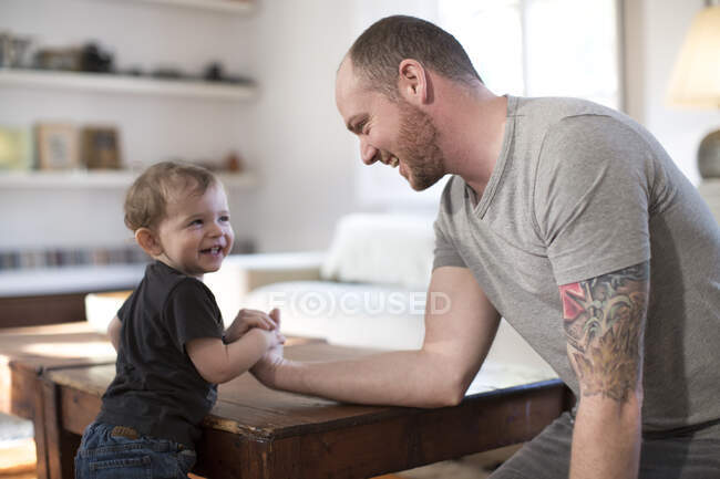 Sonriente bebé y padre brazo lucha libre - foto de stock