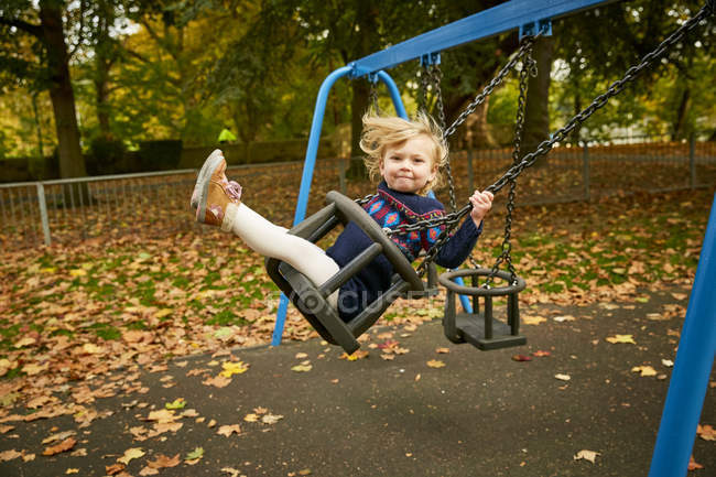 Girl swinging on playground swing — Stock Photo