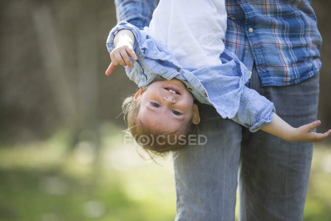 Baixa seção de pai pendurado sorrindo menino de cabeça para baixo — Fotografia de Stock