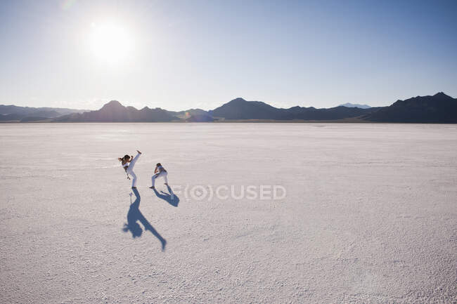 Повышенный обзор двух женщин, исполняющих капоэйру в Bonneville Salt Flats, Юта, США — стоковое фото