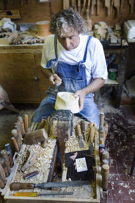 Carpenter using chisel on wooden mould for headwear in workshop — Stock Photo