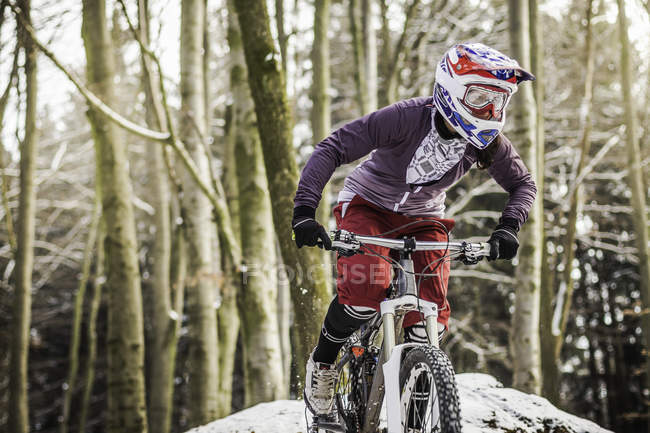 Young female mountain biker riding through forest — Stock Photo