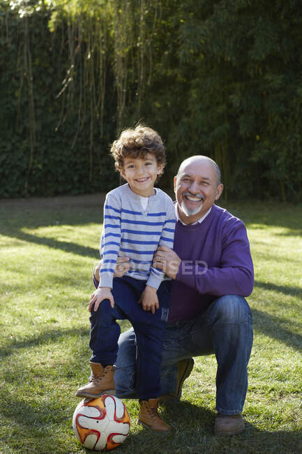 Grandfather and grandson with football looking at camera smiling — Stock Photo