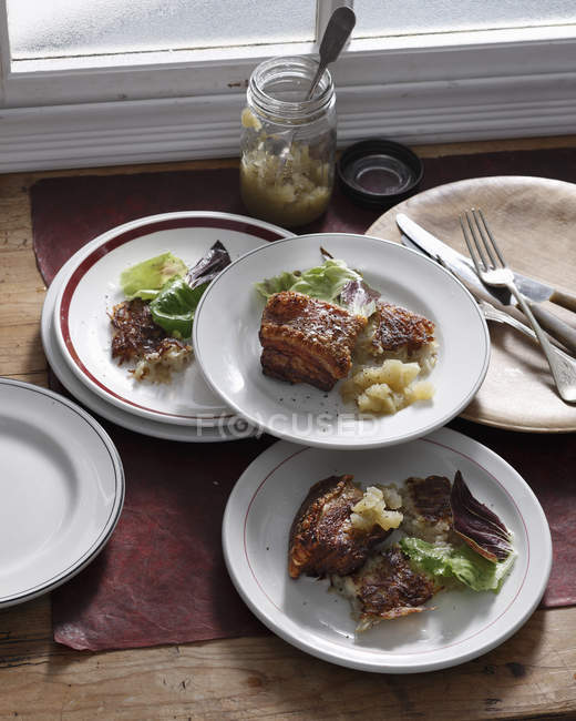 Тарілки смаженого свинячого живота з листям салату та яблучним соусом — стокове фото