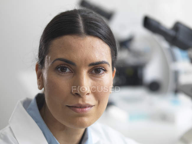 Investigadora en laboratorio junto al microscopio . - foto de stock