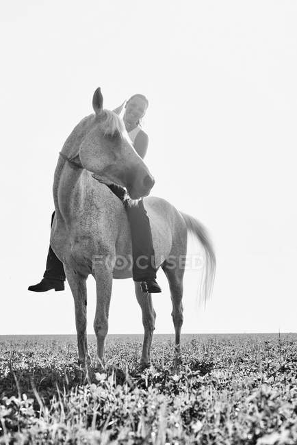 B&W portrait of woman riding horse bareback in field — Stock Photo