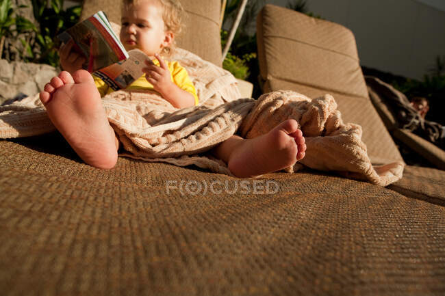 Menino de criança sentado lá fora com livro — Fotografia de Stock