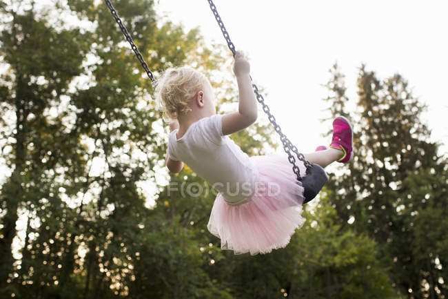 Bébé fille balançant sur l'oscillation du parc, vue arrière — Photo de stock