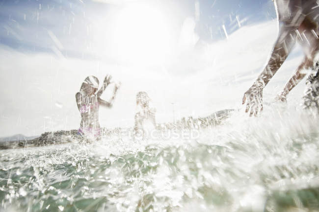 Father with son and daughter splashing each other on beach — Stock Photo