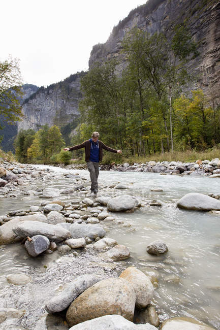 Männlicher Wanderer tritt über Felsen im Fluss, Grindelwald, Schweiz — Stockfoto