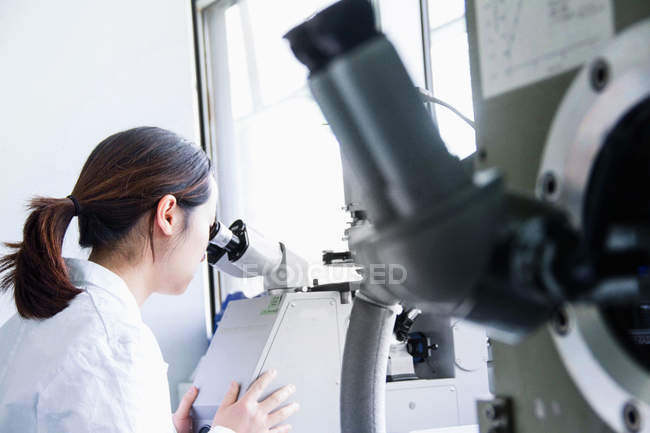 Scienziata che guarda attraverso il microscopio — Foto stock