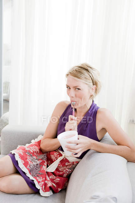 Femme sur canapé manger de la crème glacée — Photo de stock