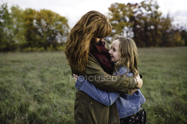 Mother and daughter hugging in meadow, Lakefield, Ontario, Canada — Stock Photo