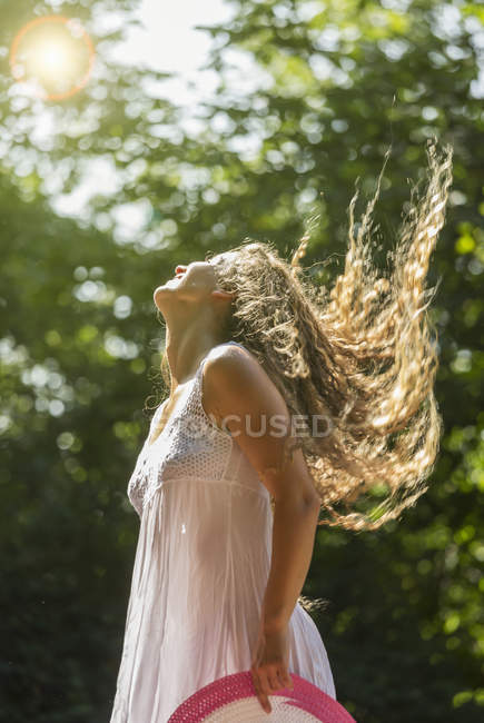 Дівчина-підліток одягнена в білий сарафан, що кидає довге волосся — стокове фото