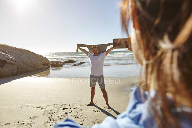 Mature woman taking photograph of man on beach, Cape Town, South Africa — Stock Photo