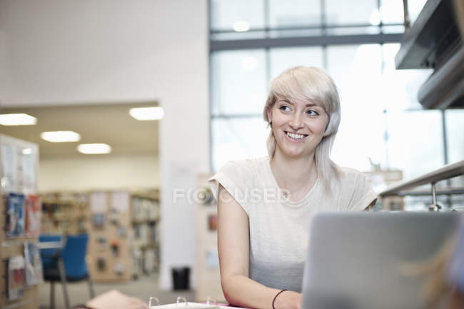 Молода жінка використовує ноутбук у бібліотеці — стокове фото
