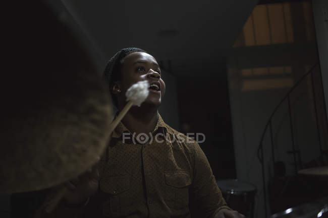 Молодой музыкант играет на барабанах в музыкальной студии — стоковое фото
