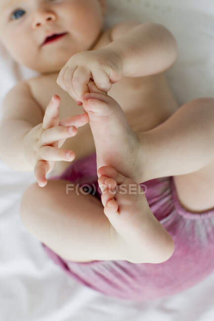 Baby girl playing with feet — Stock Photo