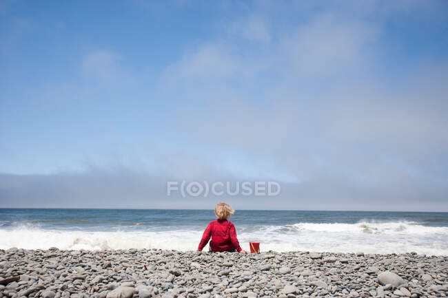 Niño sentado en el borde del agua - foto de stock
