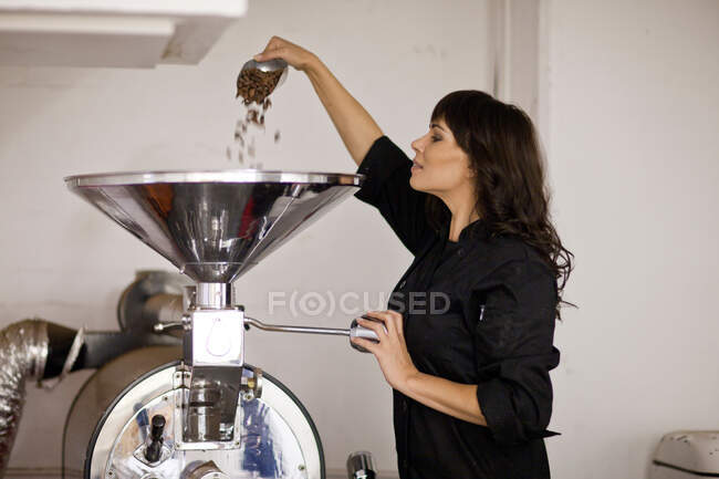 Woman pouring cocoa beans into funnel — Stock Photo