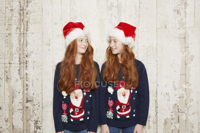 Portrait of twin sisters wearing Christmas jumpers and hats — Stock Photo