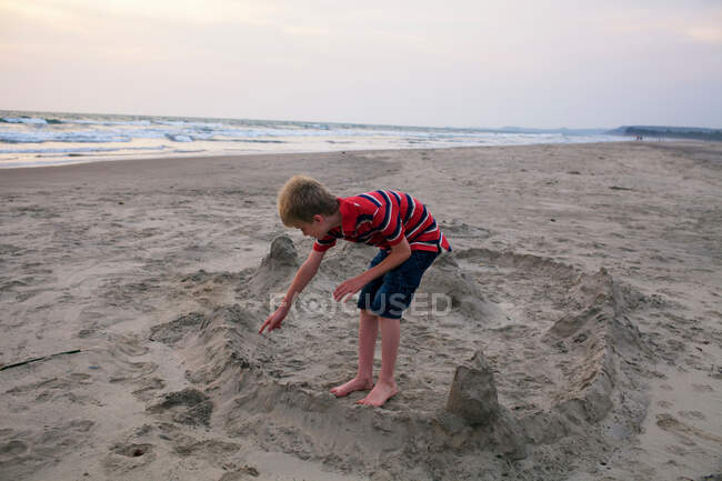 Мальчик делает песчаный замок на пляже — стоковое фото
