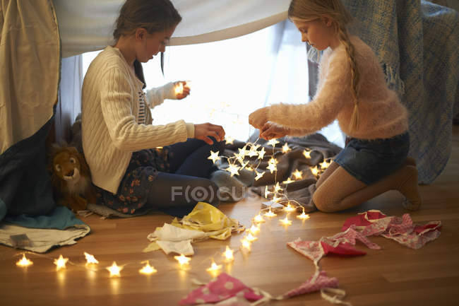 Duas irmãs no quarto den preparando luzes em forma de estrela — Fotografia de Stock