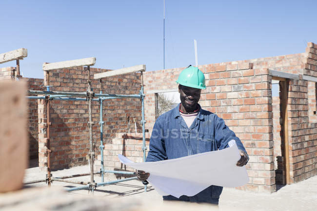 Будівельник дивиться на план на будівельному майданчику — стокове фото