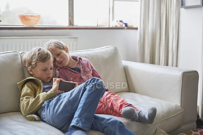 Due fratellini che usano lo smartphone a casa — Foto stock