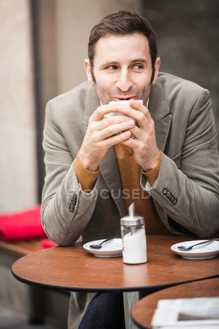 Чоловік має каву в тротуарному кафе — стокове фото