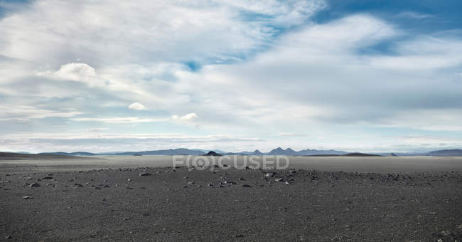 Grey barren landscape under cloudy sky — Stock Photo