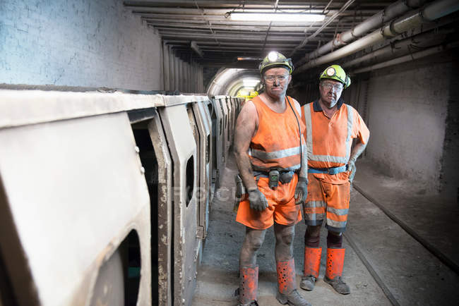 Portrait of coalminers working next to train in deep mine — Stock Photo