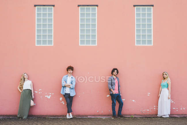 Amigos de pé contra fundo de parede rosa juntos — Fotografia de Stock