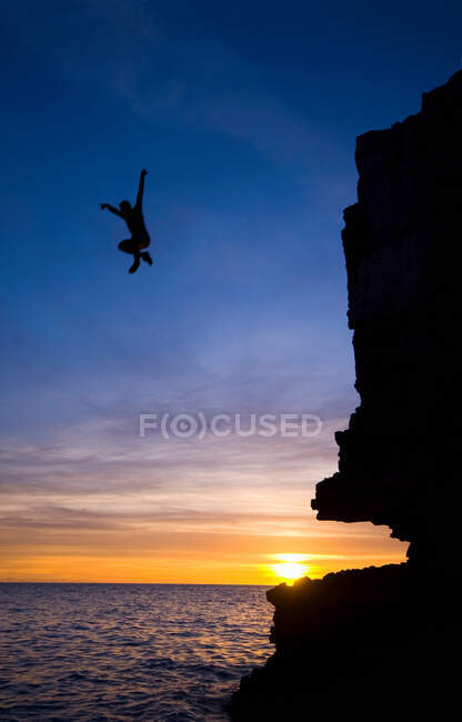 Чоловік стрибає зі скелі в океан — стокове фото