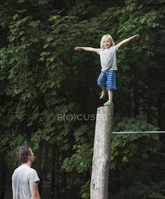 Boy on one leg, arms open, balancing on pole — Stock Photo