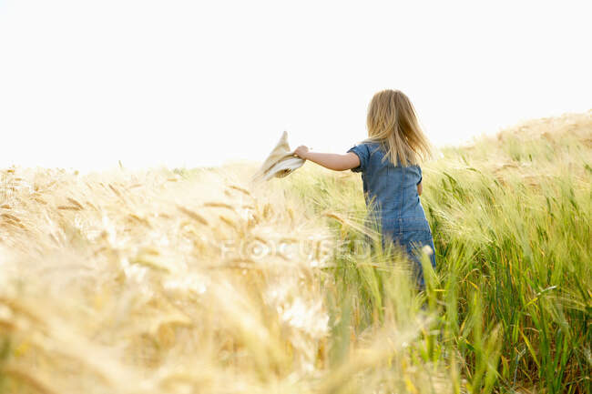 Menina correndo em um campo de trigo — Fotografia de Stock